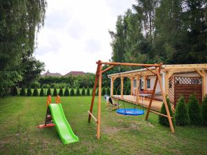 a playground with two swings and a house at Domki pod mazurskim niebem in Pilchy