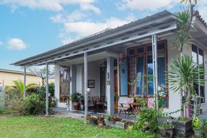 SPOT ON 93430 Delta Bnb Residence في Perabumulih: منزل أبيض صغير مع أشجار النخيل في الفناء