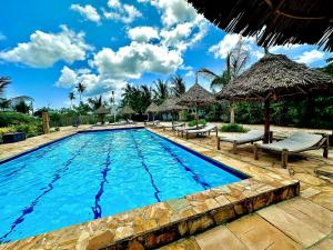a pool at a resort with chairs and umbrellas at Mambo Ocean Resort in Pwani Mchangani