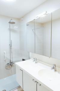 a white bathroom with two sinks and a shower at Thalassa 0201 in Bredene