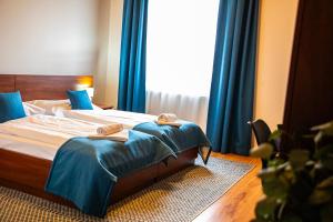 a bedroom with a bed with blue curtains and a window at Hotel Rozálka in Pezinok