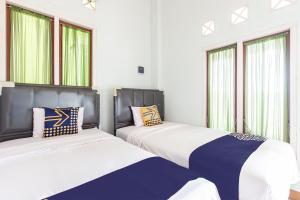2 camas sentadas una junto a la otra en una habitación con ventanas en SPOT ON 93430 Delta Bnb Residence en Perabumulih