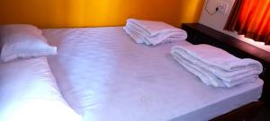 a large bed with white sheets and pillows on it at Shiva Deluxe Lodge in Shimoga