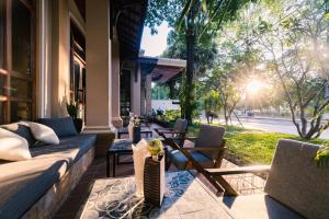 - un salon avec un canapé et des chaises sur une terrasse couverte dans l'établissement Pierre Hotel, à Siem Reap