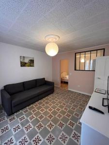 - un salon avec un canapé noir et du carrelage dans l'établissement "Le N2" Beaucaire centre-ville, à Beaucaire