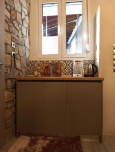 una cucina con bancone, lavandino e due finestre di Anneta s StudioBear s Path a Sklíthron