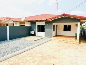 a house with a blue wall and a driveway at Wyndham Villa in Ogbojo