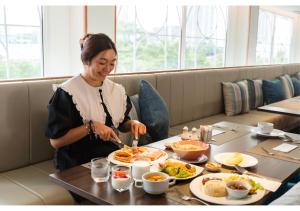 een vrouw die eten aan een tafel in een restaurant bij Away Bangkok Riverside Kene in Bangkok
