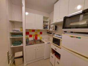 una pequeña cocina con armarios blancos y microondas en Appartement Rennes stade en Rennes