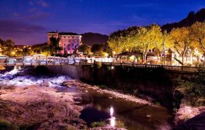 een brug over een rivier in een stad 's nachts bij Les 5 Sources in Vals-les-Bains