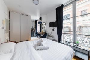 a bedroom with a white bed and a large window at Studio cosy vue sur le musée - Paris 5 - 2P in Paris
