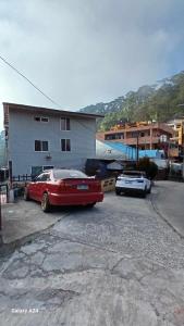 two cars parked in a parking lot next to a building at Budget Accommodation near town in Baguio