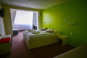 a green room with a bed and a window at Hotel OSTREDOK in Demanovska Dolina