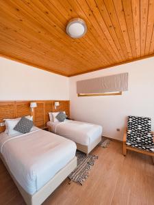 two beds in a room with a wooden ceiling at Hotel Dakhla Club in Dakhla