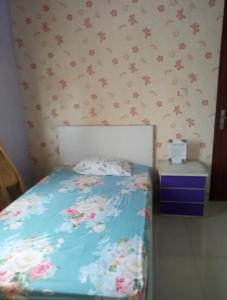 ein kleines Schlafzimmer mit einem Bett mit Blumen an der Wand in der Unterkunft cozy house in pekayon, bekasi in Pekayon Satu