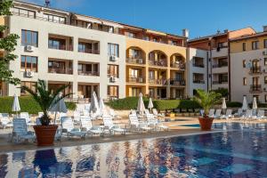 a hotel with chairs and umbrellas and a swimming pool at Galeria Holiday Apartments in Obzor