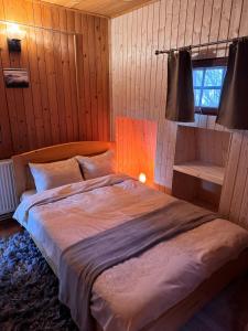 una camera da letto con un letto grande in una stanza con pareti in legno di Cabana din Padurea Valeni a Vălenii de Munte