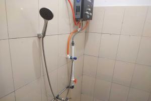 La salle de bains est pourvue d'une douche avec un pommeau de douche. dans l'établissement SPOT ON 93430 Delta Bnb Residence, à Perabumulih