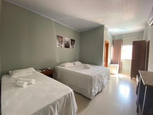 a room with two beds with white sheets at Pousada Mirante da Lua in Alto Paraíso de Goiás