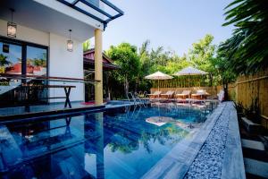 uma piscina com cadeiras e guarda-sóis ao lado de uma casa em My's Flower Villa em Hoi An