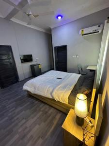 ein Schlafzimmer mit einem Bett und einem Tisch mit einer Lampe in der Unterkunft Northwold Hotel in Sotuom