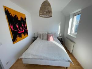 a bedroom with a white bed with a pink pillow at Traumwohnung mit Balkon im 17 Bezirk in Vienna