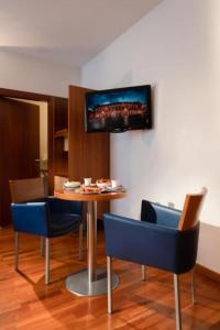 a room with a table with chairs and a tv on the wall at Best Western Hotel Fiera Verona in Verona