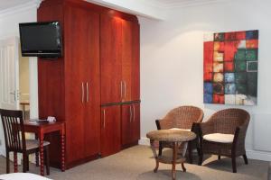 a room with a large wooden cabinet and chairs at Sir Roys Guest House in Port Elizabeth