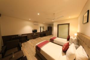 a hotel room with two beds and a television at The Byke Suraj Club, Junagadh in Junagadh