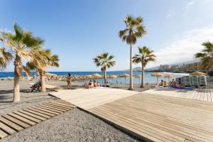 uma praia com pessoas sentadas na areia e palmeiras em Frontline Duplex Las Arenitas with pool em Candelaria