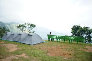 a man sitting on a bench next to a tent at Campper Eagle View Point Vagamon in Idukki