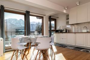 uma cozinha com mesa e cadeiras e uma grande janela em TatryTop Apartamenty Szymaszkowa Ski Premium em Zakopane