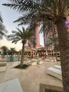 un complejo con palmeras, sillas y piscina en Fairmont Marina Abu Dhabi, en Abu Dabi