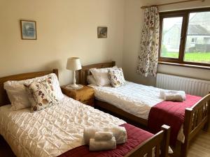 1 Schlafzimmer mit 2 Betten und einem Fenster in der Unterkunft Emerald Bank Cottage in Uldale