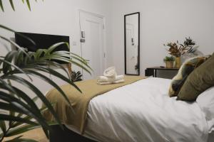 ロンドンにあるStylish Studio Apartments, Willesdenの植物と鏡付きのベッドが備わるベッドルーム1室