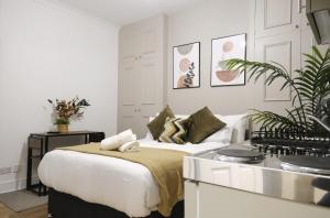 a white bedroom with a bed and a kitchen at Stylish Studio Apartments, Willesden in London