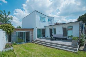 ein weißes Haus mit einer Holzterrasse im Hof in der Unterkunft Luxury retreat in Shirley North in Elmers End