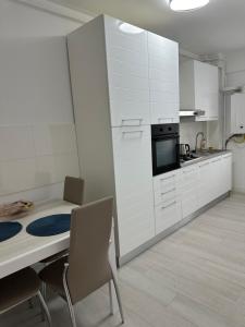 a kitchen with white cabinets and a table and chairs at Central apartment Panoramic View in Iaşi