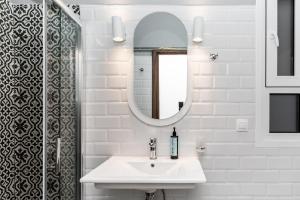 uma casa de banho branca com um lavatório e um espelho em #Alice by halu! Apartments em Tessalônica