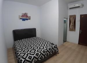 Schlafzimmer mit einem Bett mit einer schwarzen und weißen Bettdecke in der Unterkunft OYO 93306 Homestay Permana Supadio Airport in Pontianak