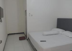 a small white room with two beds in it at OYO 93306 Homestay Permana Supadio Airport in Pontianak