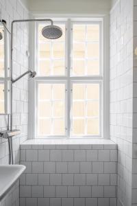 a white bathroom with a window and a bath tub at The architects' house in Stockholm