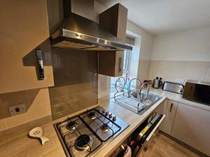 a kitchen with a stove top oven next to a counter at Cosy & Stylish One-Bed Flat-close to Warwick Uni in Coventry