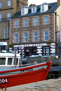 a red and white boat sitting in front of a building at St Ola Hotel in Kirkwall