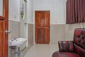 a bathroom with a sink and a wooden door at Super OYO 2226 Nurmega Jaya in Sukabumi