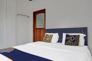 a bed with blue and white pillows on it at Super OYO 2226 Nurmega Jaya in Sukabumi