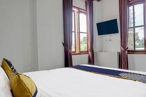 a bedroom with a bed with white sheets and windows at Super OYO 2226 Nurmega Jaya in Sukabumi