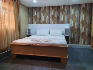 1 dormitorio con 1 cama grande y pared de madera en Mum's Hotel And Accommodation, 