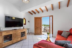 a living room with a tv and a red couch at Villa Maeva - PlusHolidays in Casas de Torrat