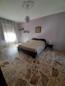 Schlafzimmer mit einem Bett und Steinboden in der Unterkunft Tindara's House in Francavilla di Sicilia